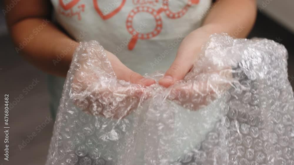 Baby girl playing with bubble wrap. Girl pressing the bubble wrapping replaces spinner, slime and pop it. Stress Calming the nervous system concept Baby girl playing with bubble wrap. Girl pressing the bubble wrapping replaces spinner, slime and pop it. Stress Calming the nervous system concept