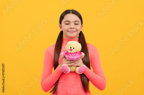 dreamy child with teddy bear toy for valentines day on yellow background, dream