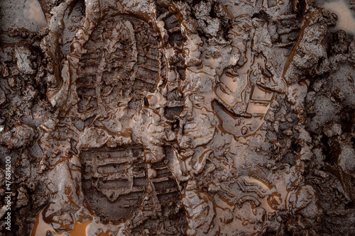 A boot print in the mud close-up. Footprint in the dirt. Bottom of shoes.