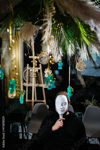 Portrait of man at table wearing mafia mask surrounded by Christmas decoration