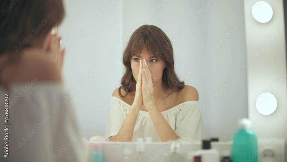 Distressed woman with vitiligo skin sitting in front mirror nervous before event Distressed woman with vitiligo skin sitting in front mirror nervous before event