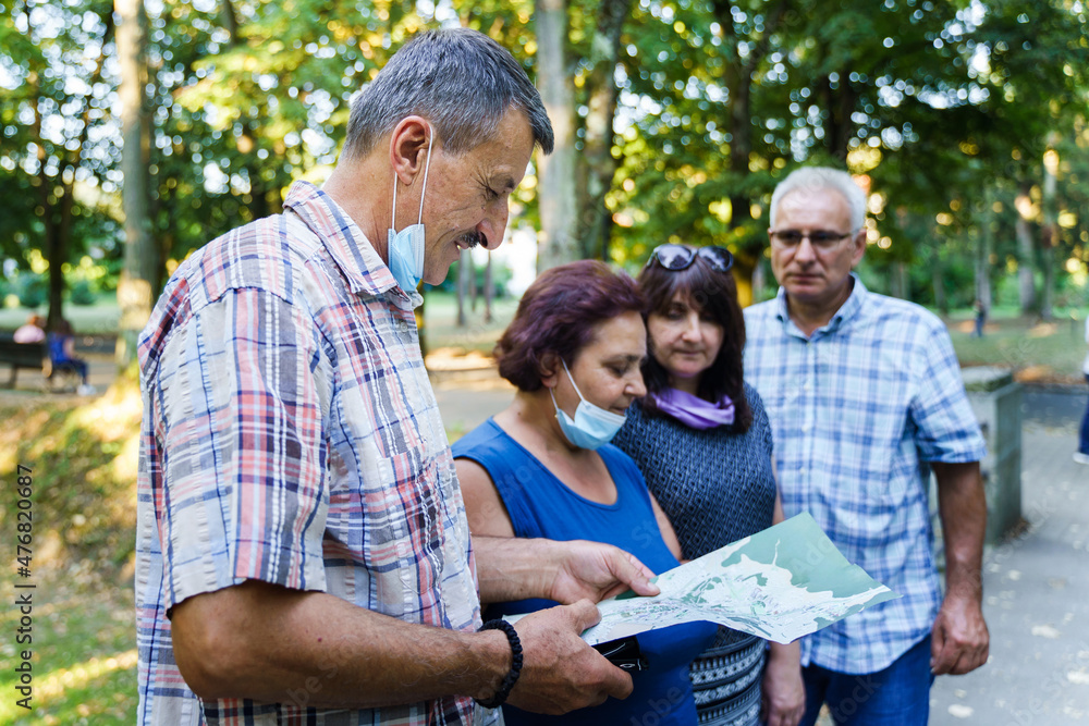 Group of senior friends tourists in autumn or summer day - Mature man showing to his wife and company location on the map and instructions about the route - real people tourism concept Group of senior friends tourists in autumn or summer day - Mature man showing to his wife and company location on the map and instructions about the route - real people tourism concept