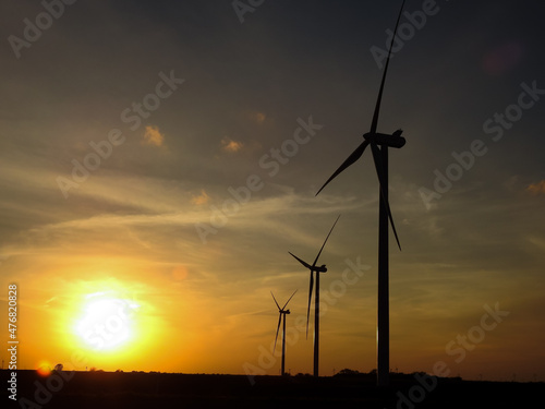 Huge Wind Power Turbines Silhouetted by a Sunset on the Horizon