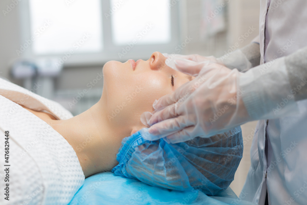 Side view of a girl relaxing on a couch during a facial massage in a beauty salon. Moisturizing and rejuvenation of the facial skin Side view of a girl relaxing on a couch during a facial massage in a beauty salon. Moisturizing and rejuvenation of the facial skin