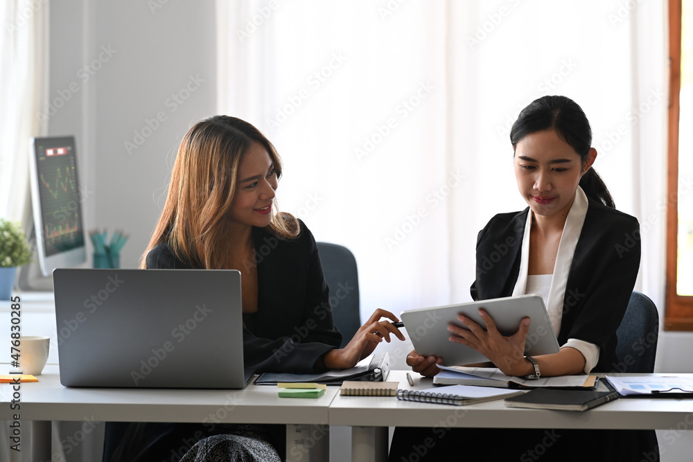 Two beautiful business women working on project together in modern workplace. Two beautiful business women working on project together in modern workplace.