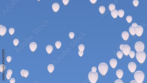 Many white balloons rise into the blue sky close to the camera.