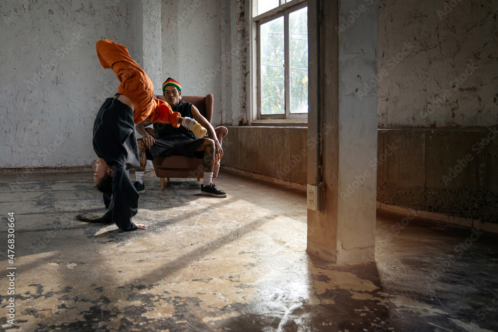 Fototapeta premium Couple dancers practice break dance in empty room, sunlight shining into the room, Tattoo on body