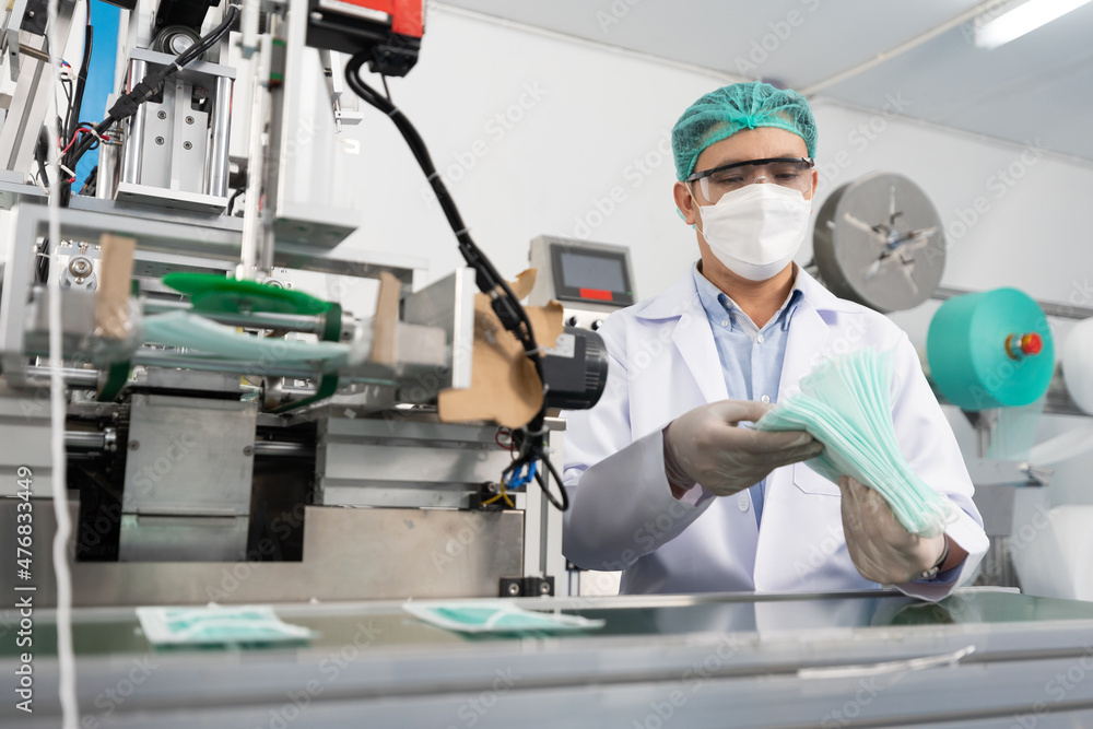 male factory worker are producing medical face masks, counting and checking of quality from machine male factory worker are producing medical face masks, counting and checking of quality from machine