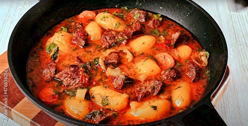 stewed meat with potatoes and vegetables in a frying pan