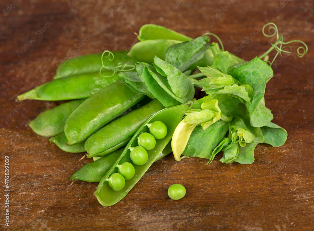 Green peas with leaves on wooden background Green peas with leaves on wooden background