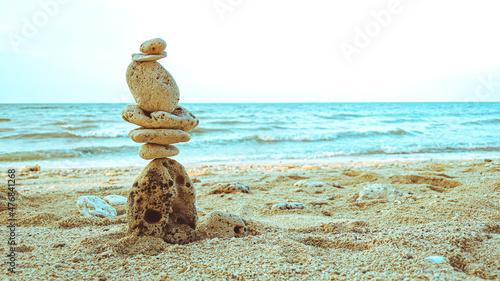 Rocks balanced on clean sand with beach background showing the concept of harmony