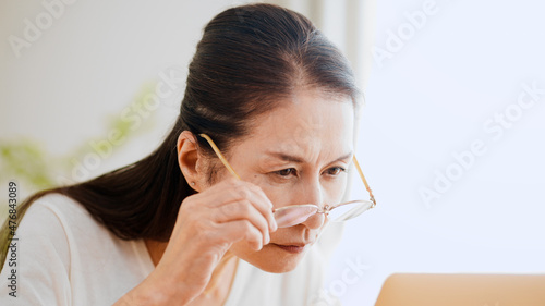 Foto 老眼鏡でノートパソコンを覗くシニア女性
