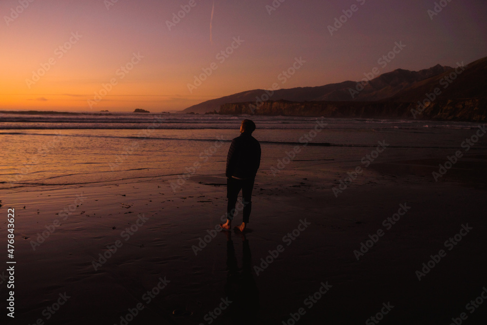 silhouette of a person man walking on the beach at sunset in big sur