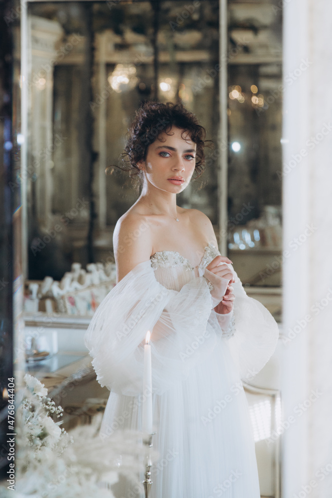 Beautiful curly-haired bride in a luxury wedding dress in a restaurant with wedding decor