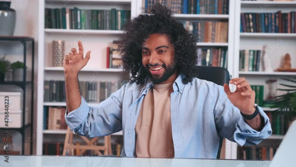 Cheerful attractive young Indian man freelancer with curly hairstyle