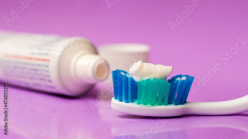 Toothbrush and tube of toothpaste on a purple background. Dental care