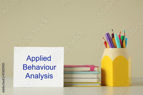 Set of stationery and card with text Applied Behavior Analysis on wooden table against beige background