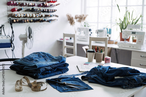 Reuse, repair, upcycle. Sustainable fashion, Circular economy. Denim upcycling ideas, repair and using old jeans. Close-up of old denim jeans fabric stack in Sewing studio. photo