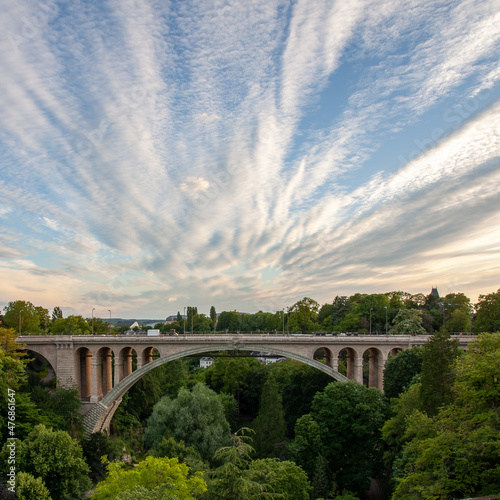 Amazing view from the unique Adolf bridge in Luxembourg surrounded by green trees under blue sky and white clouds during daytime photo and amazing weather