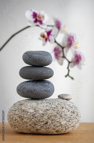Stack of gray stones built in tower isolated on white background with white purple orchid flower on long stem