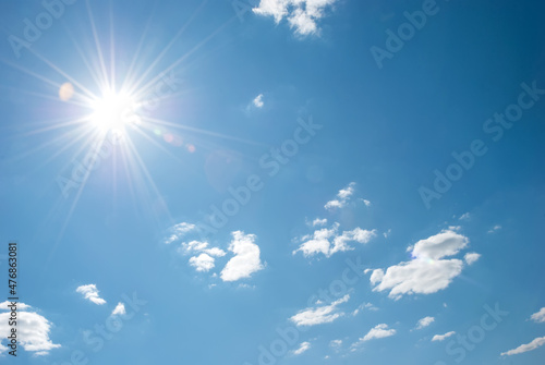 Beautiful, blue summer sky with fluffy clouds and bright sun as a background