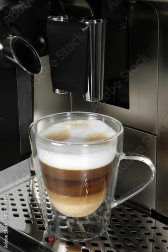 Modern coffee machine with glass cup of latte  closeup