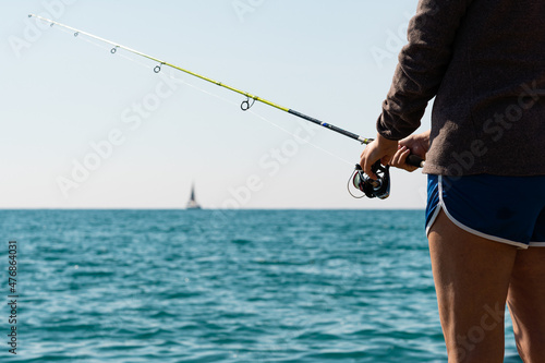 Close-up of man holding a fishing rod near the sea.