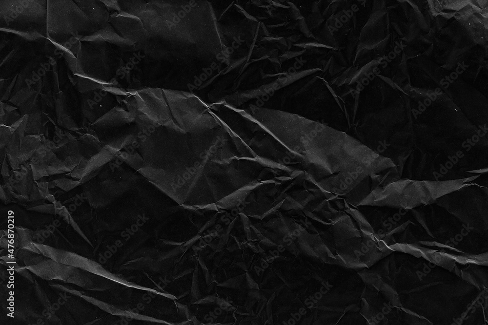 Black crumpled paper texture with folds. Black grunge surface. Black