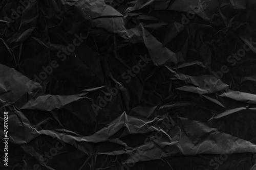 Black crumpled paper texture with folds. Black grunge surface. Black wallpaper background. 