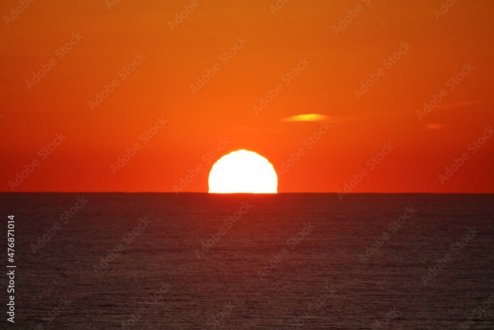 Sunset along the Atlantic ocean with birds in the foreground silhouetted against the sky fire.    