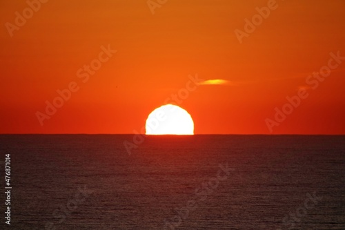 Sunset along the Atlantic ocean with birds in the foreground silhouetted against the sky fire.    