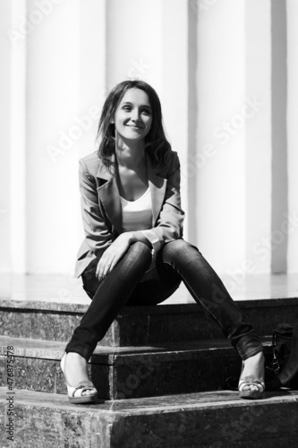 Young fashion woman in gray blazer sitting on steps