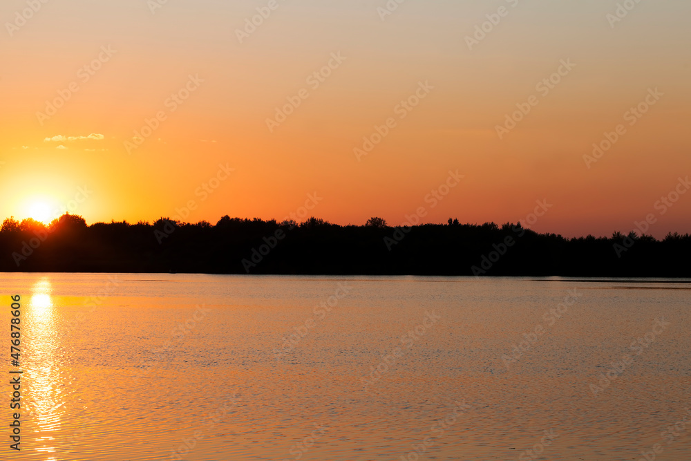 Naklejka premium lake during sunset with yellow-orange sky