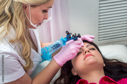 Young woman doing eyebrow microblading in a beauty salon  photo