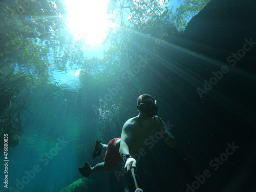Fototapeta Naklejka Na Ścianę i Meble -  Man takes selfie while freediving in Casa Cenote in Tulum, Quintana Roo, Mexico
