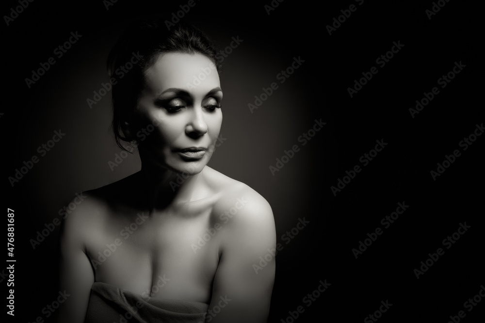 Portrait of a sensual fifty year old woman on grey studio background. Monochrome shot. Portrait of a sensual fifty year old woman on grey studio background. Monochrome shot.