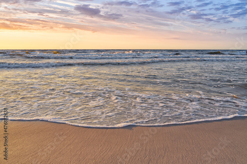 Sunset on Baltic Sea white pastel color sky and rough sea. 