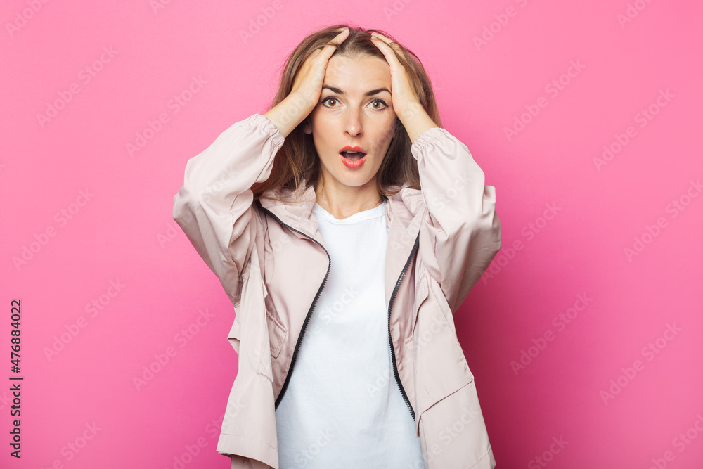 Surprised young woman in pink jacket, pink isolated background Surprised young woman in pink jacket, pink isolated background