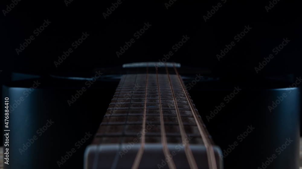 hand touching the strings of the guitar. black guitar fretboard