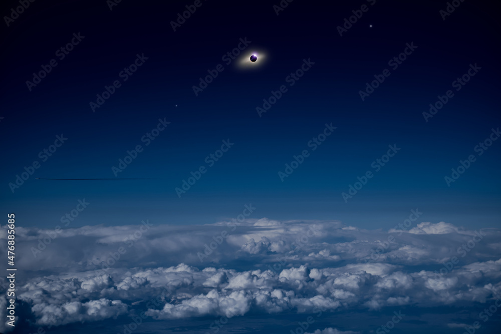Solar eclipse on a dark blue sky above clouds and atmosphere.