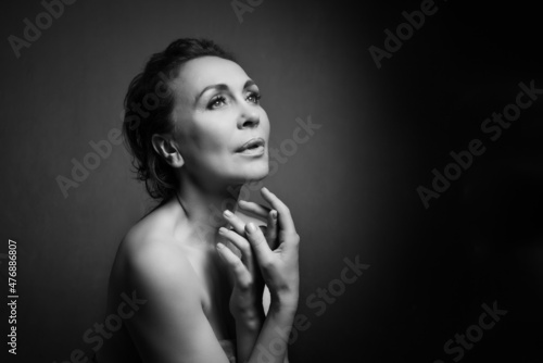 Portrait of a sensual fifty year old woman on grey studio background. Monochrome shot. © Igor Borodin
