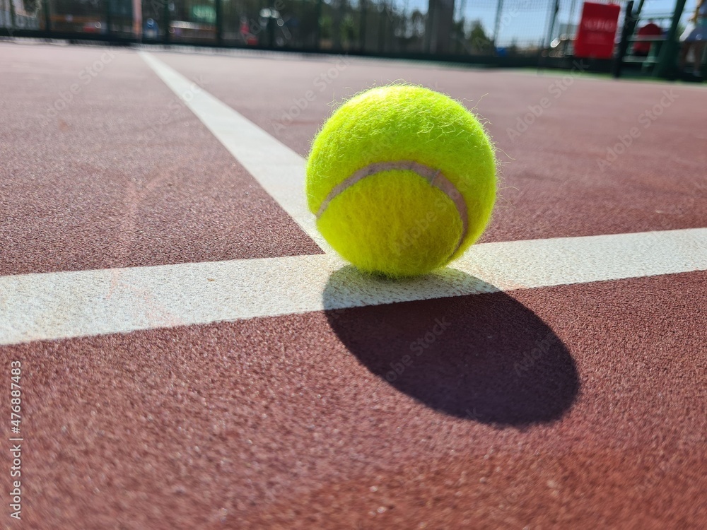 Tennis ball on the sunny hard court аnd the service line.