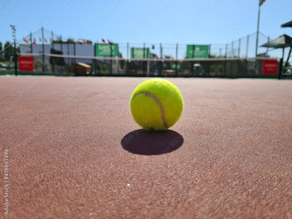 Tennis ball on the sunny hard court at the midday.