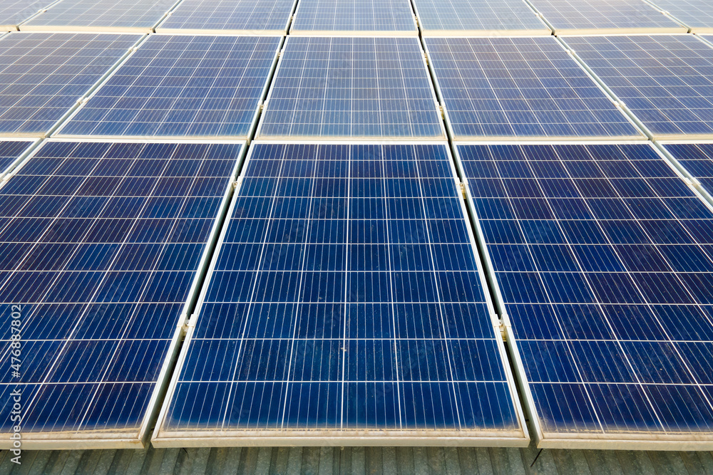 Closeup of surface of blue photovoltaic solar panels mounted on building roof for producing clean ecological electricity. Production of renewable energy concept Closeup of surface of blue photovoltaic solar panels mounted on building roof for producing clean ecological electricity. Production of renewable energy concept
