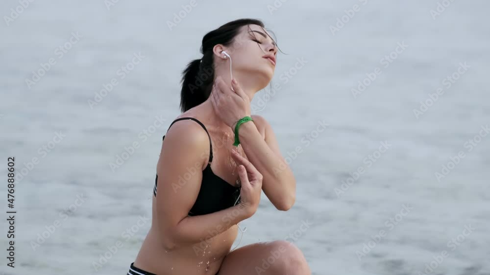 Woman after jogging. woman resting after jogging on the beach. Young woman wears headphones to listen to music while running. Exercise to prevent coronavirus and the new normal concept Woman after jogging. woman resting after jogging on the beach. Young woman wears headphones to listen to music while running. Exercise to prevent coronavirus and the new normal concept