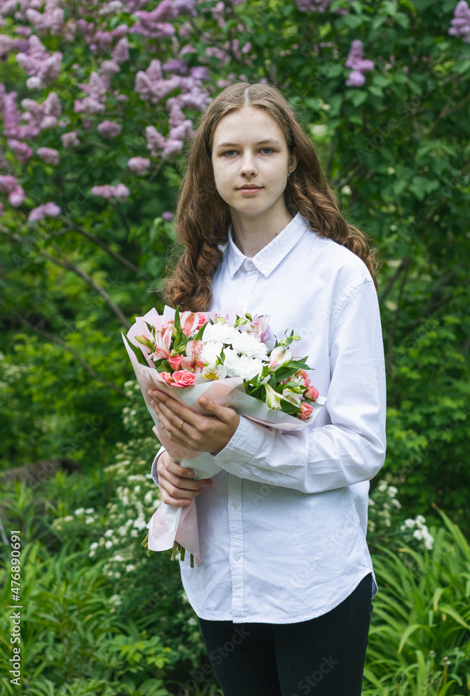 Young beautiful girl, portrait in the garden on a background of lilacs. A girl in a white blouse holds a beautiful bouquet of flowers in her hands. Young beautiful girl, portrait in the garden on a background of lilacs. A girl in a white blouse holds a beautiful bouquet of flowers in her hands.