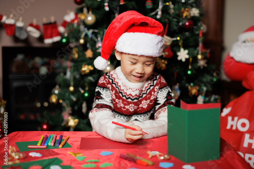 medium shot young girl making Christmas card in front of Christmas tree