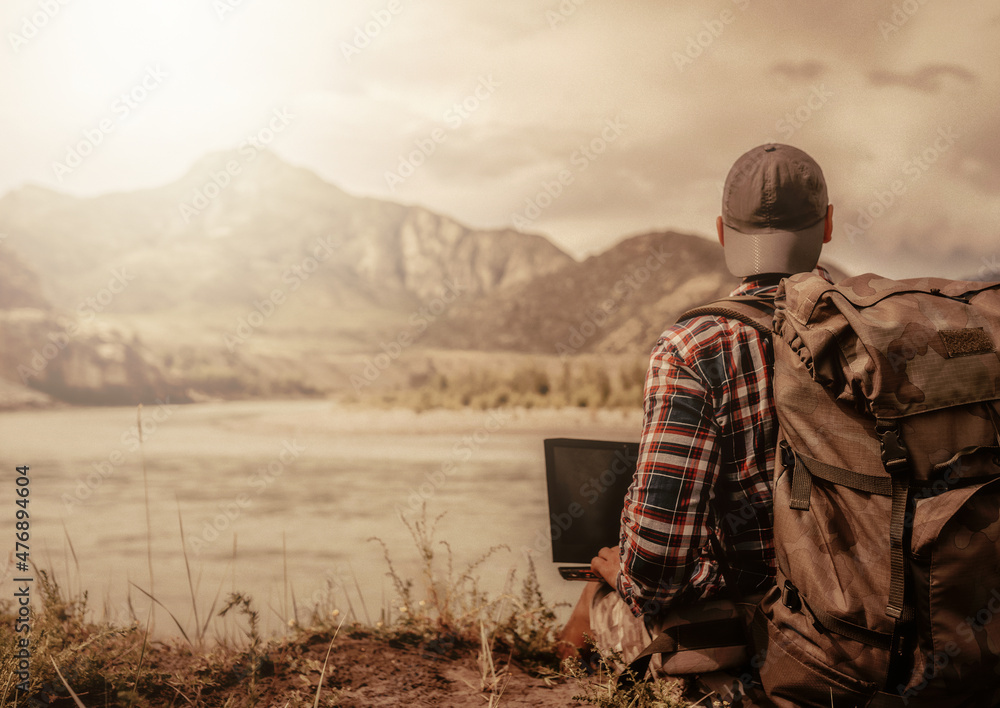 men with backpack and laptop on the beach of river men with backpack and laptop on the beach of river
