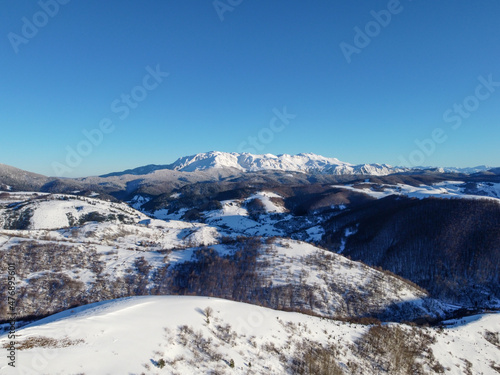 Aerial drone view of hills and forest covered with a snow. Mountain in winter.