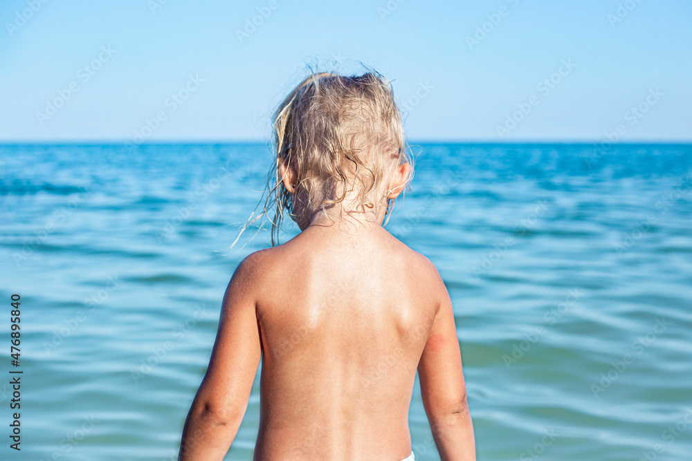 Child girl standing with her back looking at the sea on the beach. Child girl standing with her back looking at the sea on the beach.